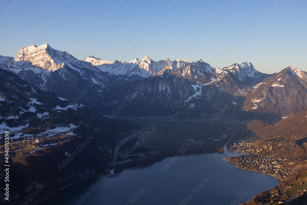 Great view on a beautiful morning over a lake called Walensee. The mountains in the background are illuminated by the morning sun. Great view on a beautiful morning over a lake called Walensee. The mountains in the background are illuminated by the morning sun.