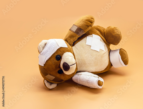 torn children's toy with bandages and bandages, concept of childhood violence or child aggression photo