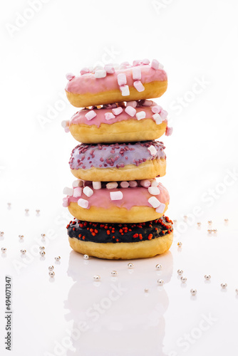 Shot of five sweet doughnuts stacked on top of each other in the form of a tower. Tasty delicious sweet donut with colorful sprinkles on white background.