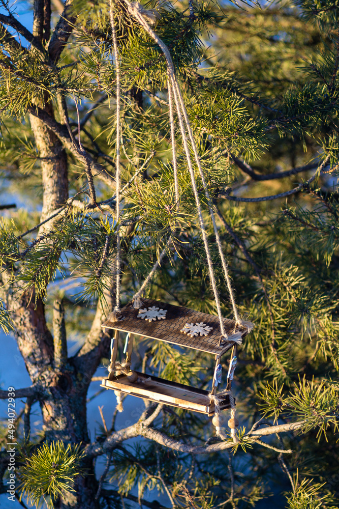 Wooden bird feeder on a coniferous tree