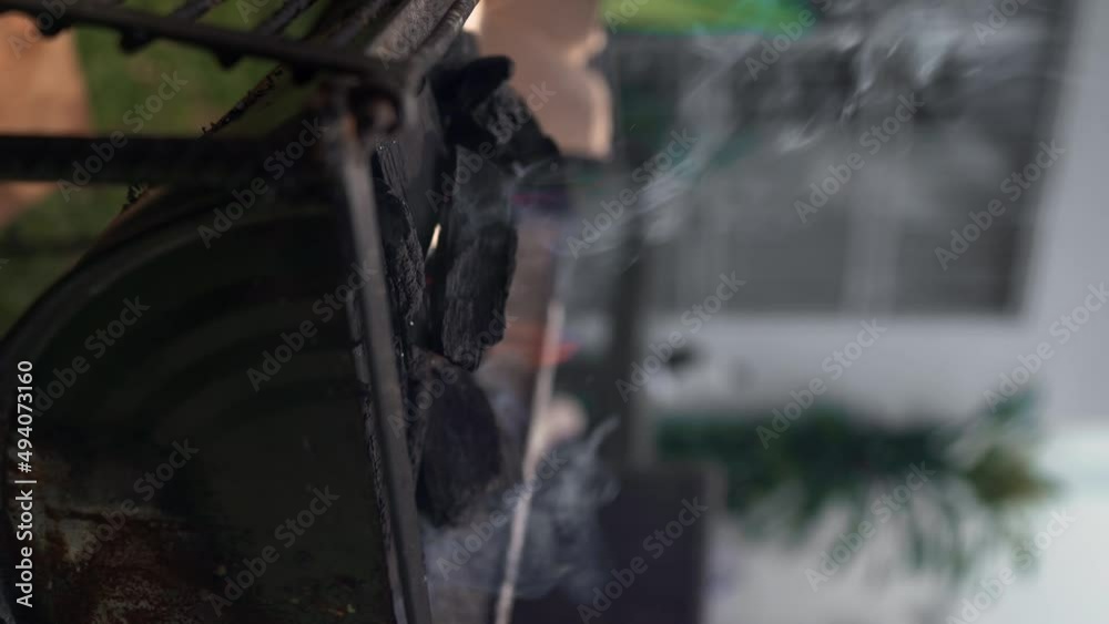 vertical shot - man makes fire with charcoal on a grill vertical shot - man makes fire with charcoal on a grill