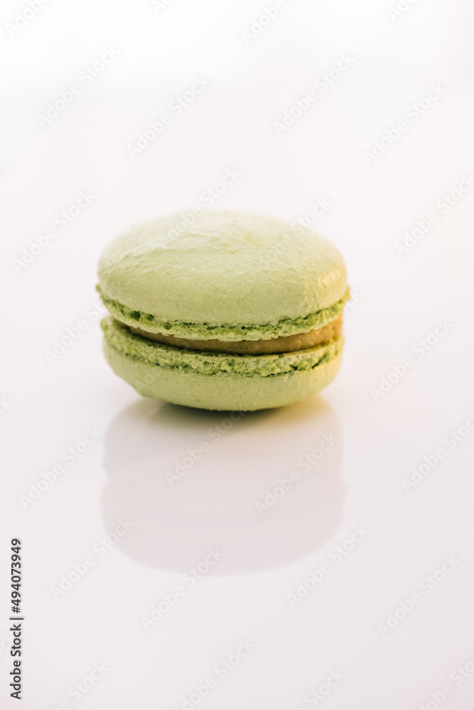 Colorful cake macaroons isolated on abstract background. Traditional French multicolored macaroon. Green macaron pastries on white background. Food concept. Colorful cake macaroons isolated on abstract background. Traditional French multicolored macaroon. Green macaron pastries on white background. Food concept.