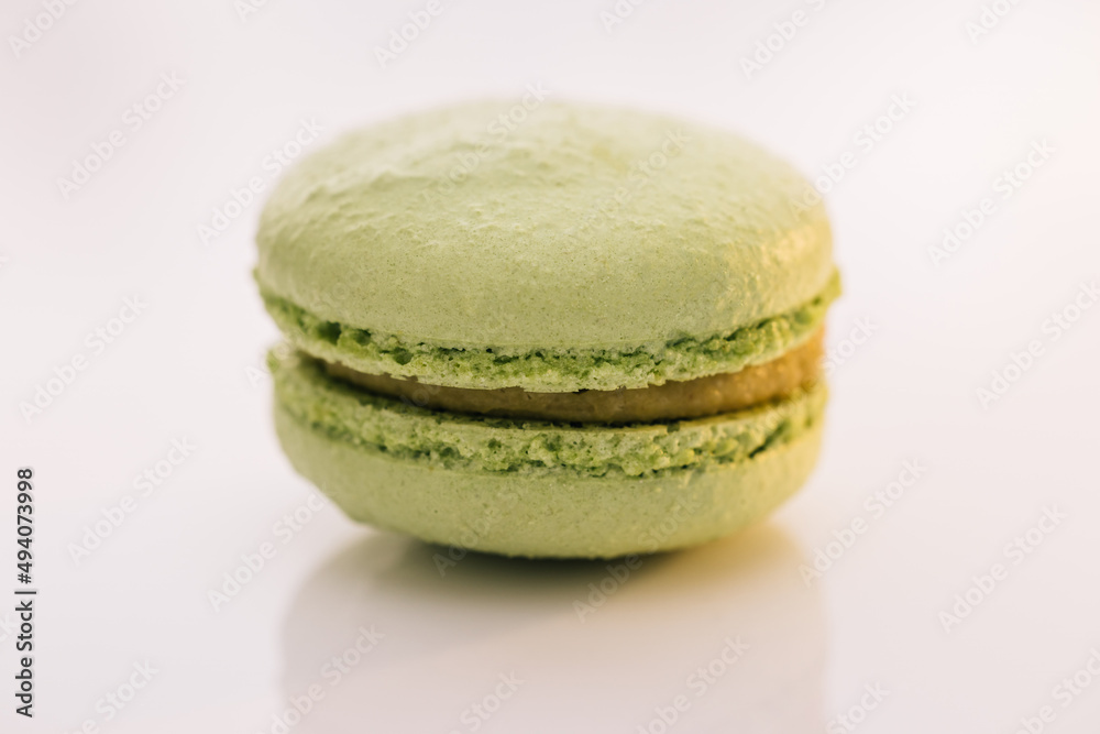 Green macaron pastries on white background. Colorful cake macaroons isolated on abstract background. Traditional French multicolored macaroon. Food concept