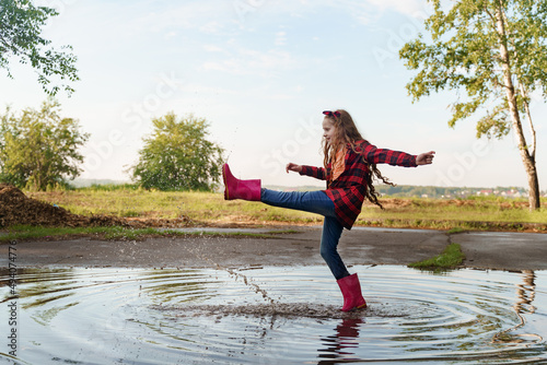 Child with rain boots run into a puddle. photo