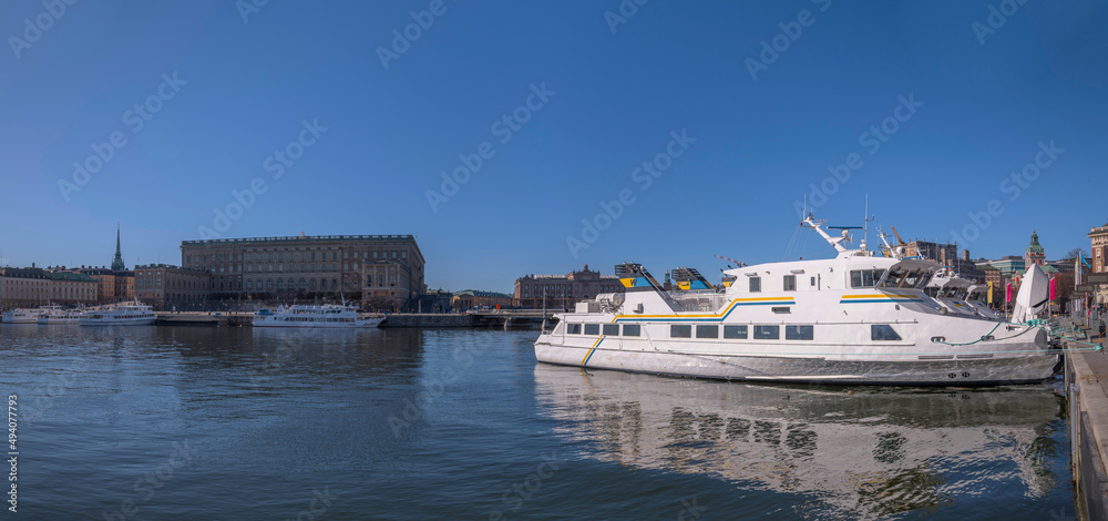 Morning panorama view over the bay Strömmen, commuting boats at the pier Strömkajen and the old town Gamla Stan in background a sunny spring day in Stockholm