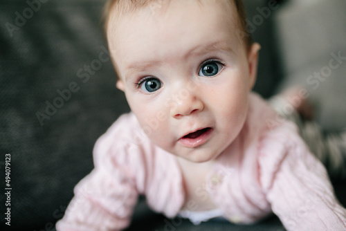 Cute baby girl in pink cardigan making a funny face