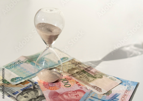 Rubles, dollars, yuans and hourglass on the white background. Time is money concept
