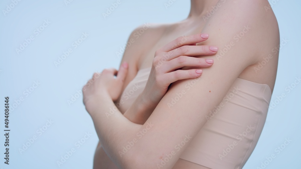 Fototapeta premium Low angle beauty portrait of young redhead woman gently touches her body sliding both of her hands from her arms