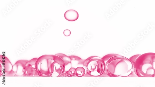 Macro shot of pink clear different sized bubbles are falling down on white background | Abstract skin care cosmetics with retinol formulation concept photo