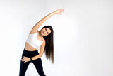 Portrait of mature girl stretching her arms on white background. Attractive brunette woman in fashionable sportswear exercising. Healthy lifestyle, sport concept