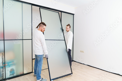 masters install sliding doors of wardrobe made of metal and glass.
