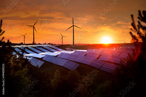 Solar panels station and wind power generator equipment at sunset time, alter...