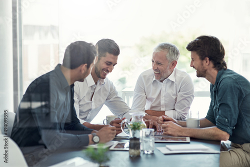 This boardroom is filled with positivity. Shot of a group of businessmen having a meeting around a table in an office.