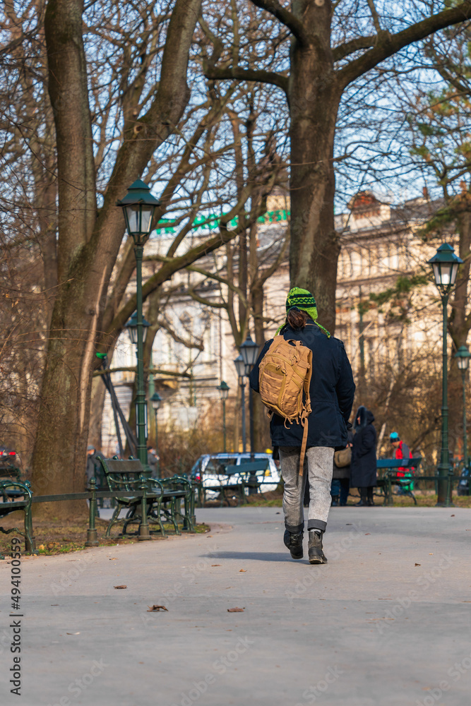 A tourist with a backpack walks along the street of a European city on a sunny spring day A tourist with a backpack walks along the street of a European city on a sunny spring day