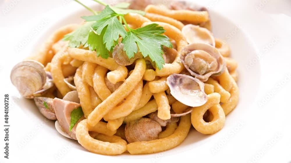 Vongole pasta in a white plate with hot steam. Fresh lunch in a traditional Italian restaurant thick pasta with clams and parsley, close-up. High quality FullHD footage Vongole pasta in a white plate with hot steam. Fresh lunch in a traditional Italian restaurant thick pasta with clams and parsley, close-up. High quality FullHD footage