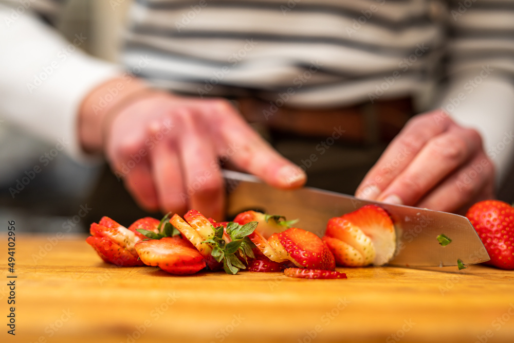 Woman in the kitchen cutting strawberries on a wooden cutting board Woman in the kitchen cutting strawberries on a wooden cutting board