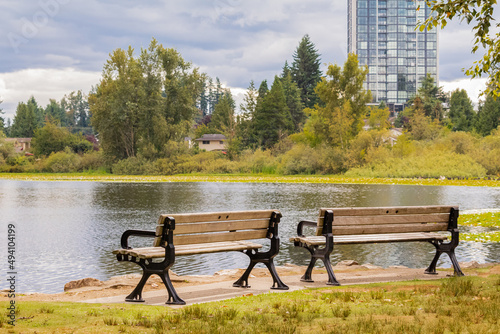 Two park benches in front of lake in outcast day.