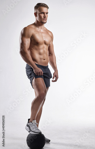 If you have free time, spend it in the gym. Studio shot of a muscular man standing with his foot on an exercise ball.