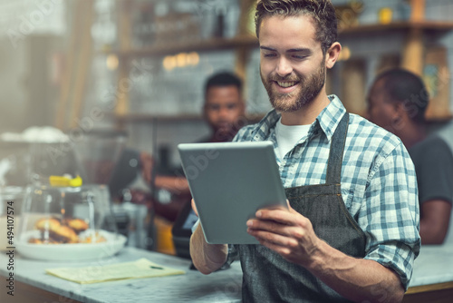 Social media is great for boosting small business visibility. Shot of a young man using a digital tablet in the store that he works at.