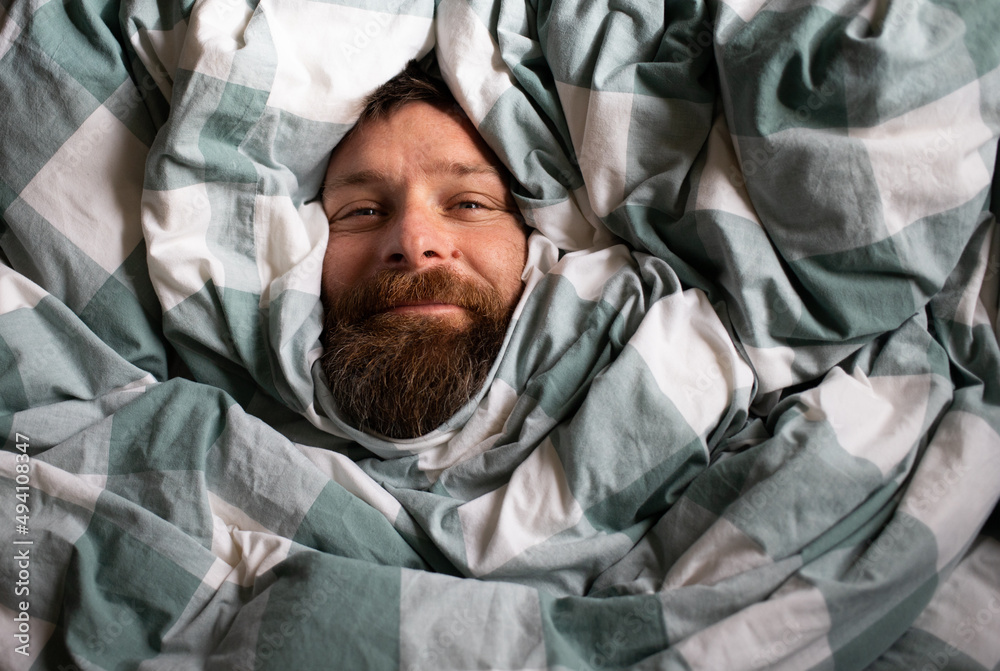 happy relaxed man portrait sleeping in duvet