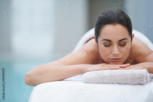 Enjoying a day at the spa. Shot of a beautiful woman lying on a poolside massage table.