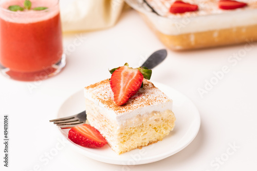 Fototapeta Naklejka Na Ścianę i Meble -  a piece of tres leches cake with a glass of strawberry margarita on a white background