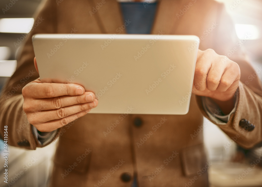 Digital design. Low angle shot of an unrecognizable male designer working on a tablet in his office. Digital design. Low angle shot of an unrecognizable male designer working on a tablet in his office.