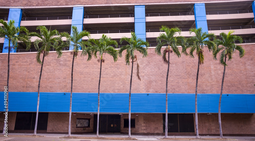 Red Brick ParkingGarage with Blue Awning and Palms. photo