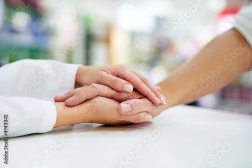 Kindness goes a long way towards healing. Cropped shot of a pharmacist compassionately holding a customers hand.