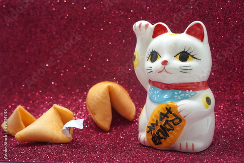 Lunar new year lucky cat maneki neko with fortune cookies on red background