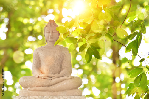 Buddha statue on green blurred nature background. Buddhist holy days concept.
