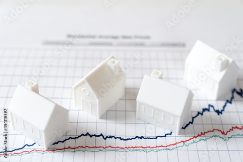 White miniature house models on graph indicating growth in real estate prices market