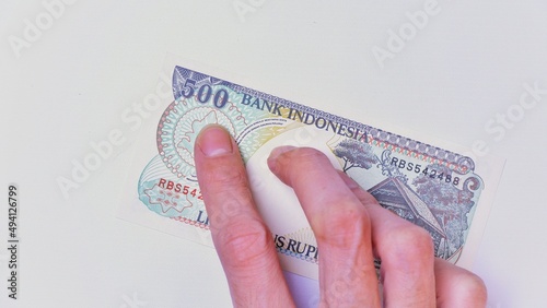 Indonesian Rupiah the official currency of Indonesia. Male hand showing Indonesian Rupiah note. Business Investment Economy Money and Finance Concept Uang 500 Rupiah Kuno Vintage and ancient concept. photo