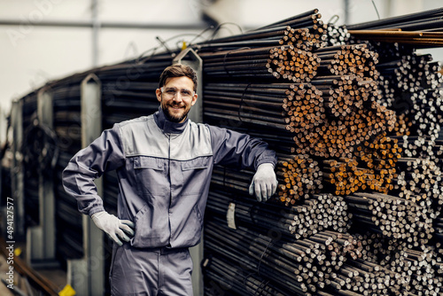 Portrait of proud metallurgy worker leaning on metal framework in steel factory. photo