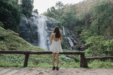 A beautiful woman stood looking at a large beautiful waterfall.