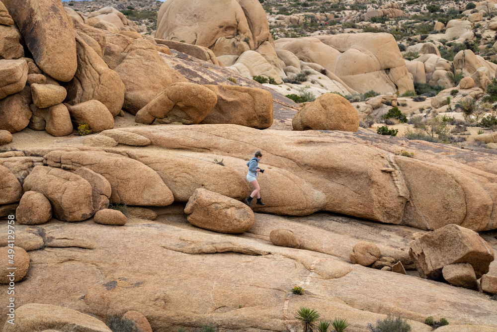 Woman hiking in Joshua Tree National Park, climbing over large boulder rocks. Woman hiking in Joshua Tree National Park, climbing over large boulder rocks.