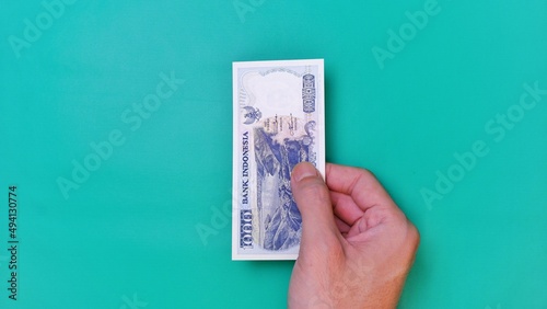 Indonesian Rupiah the official currency of Indonesia. Man's hand is making a payment. Male hand showing Indonesian Rupiah note. Business Investment Economy and Finance concept. Uang 1000 1.000 Rupiah