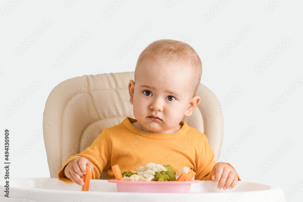 Toddler does not like vegetarian food, the child sitting on a feeding chair refuses to eat boiled vegetables Toddler does not like vegetarian food, the child sitting on a feeding chair refuses to eat boiled vegetables