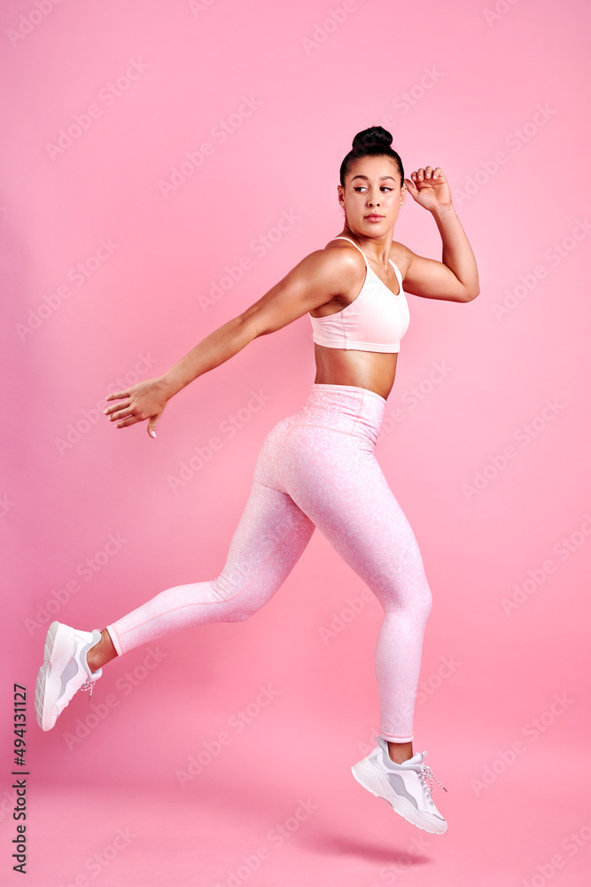 Im going to keep on powering on. Studio shot of a sporty young woman jumping against a pink background. Im going to keep on powering on. Studio shot of a sporty young woman jumping against a pink background.
