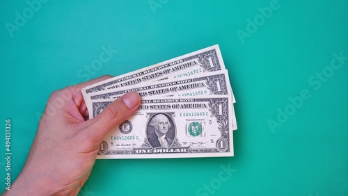 Man's hand is making a payment. Business Investment Economy Money Loan Saving Income and Finance concept. Male hand showing dollar bills on green background. One Dollar. 1 USD. Prosperity concept.