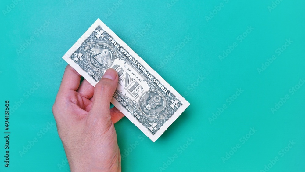 Man's hand is making a payment. Business Investment Economy Money Loan Saving Income and Finance concept. Male hand showing dollar bills on green background. One Dollar. 1 USD. Prosperity concept. Man's hand is making a payment. Business Investment Economy Money Loan Saving Income and Finance concept. Male hand showing dollar bills on green background. One Dollar. 1 USD. Prosperity concept.
