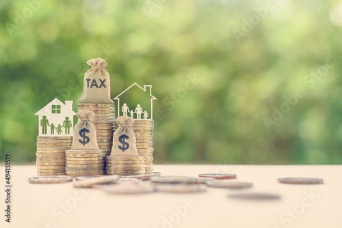 Family tax benefit / residential property or estate tax concept : Tax burlap bag, family members, house on rows of coin money, depicts mandatory financial charge / type of levy imposed upon a taxpayer