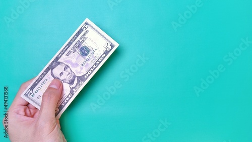Man's hand is making a payment. Business Investment Economy Money Loan Saving Income and Finance concept. Male hand showing dollar bills on green background. Five Dollar. 5 USD. Prosperity concept.