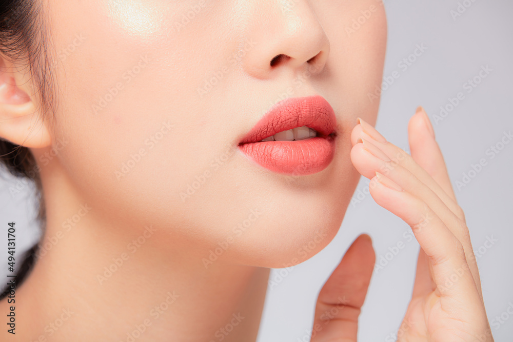 Obraz premium A close view of model showing lip posing with hand for cosmetic advertising