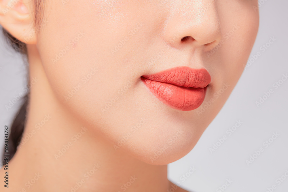 A close view of model showing lip posing with hand for cosmetic advertising