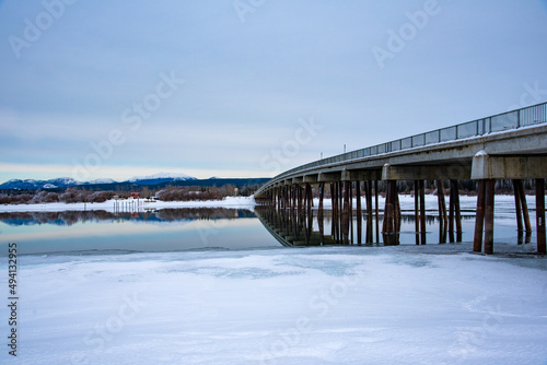 Winter time in northern Canada landscape over the Tagish River with cloudy sky above long bridge.  © Scalia Media