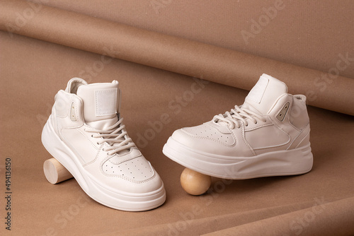 Eco leather shoes. A pair of beige sneakers on brown background. Minimal style. Casual sport lifestyle concept