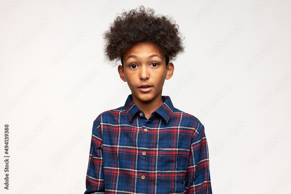 Studio shot of puzzled boy of black ethnicity with afro hair in flannel  blue shirt looking at camera with big round-shaped eyes and mouth, feeling  surprised. Human emotions and feelings Stock Photo |