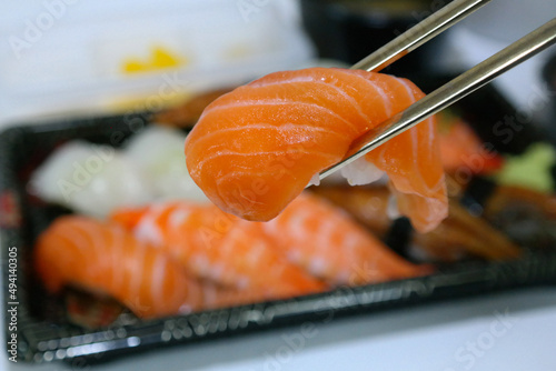 Pick up the salmon sushi from the lunch box with your chopsticks.
