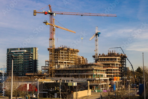 Construction of high-rise buildings in Richmond City, industrial construction site, construction equipment, several construction cranes on the background of a blue cloudy sky